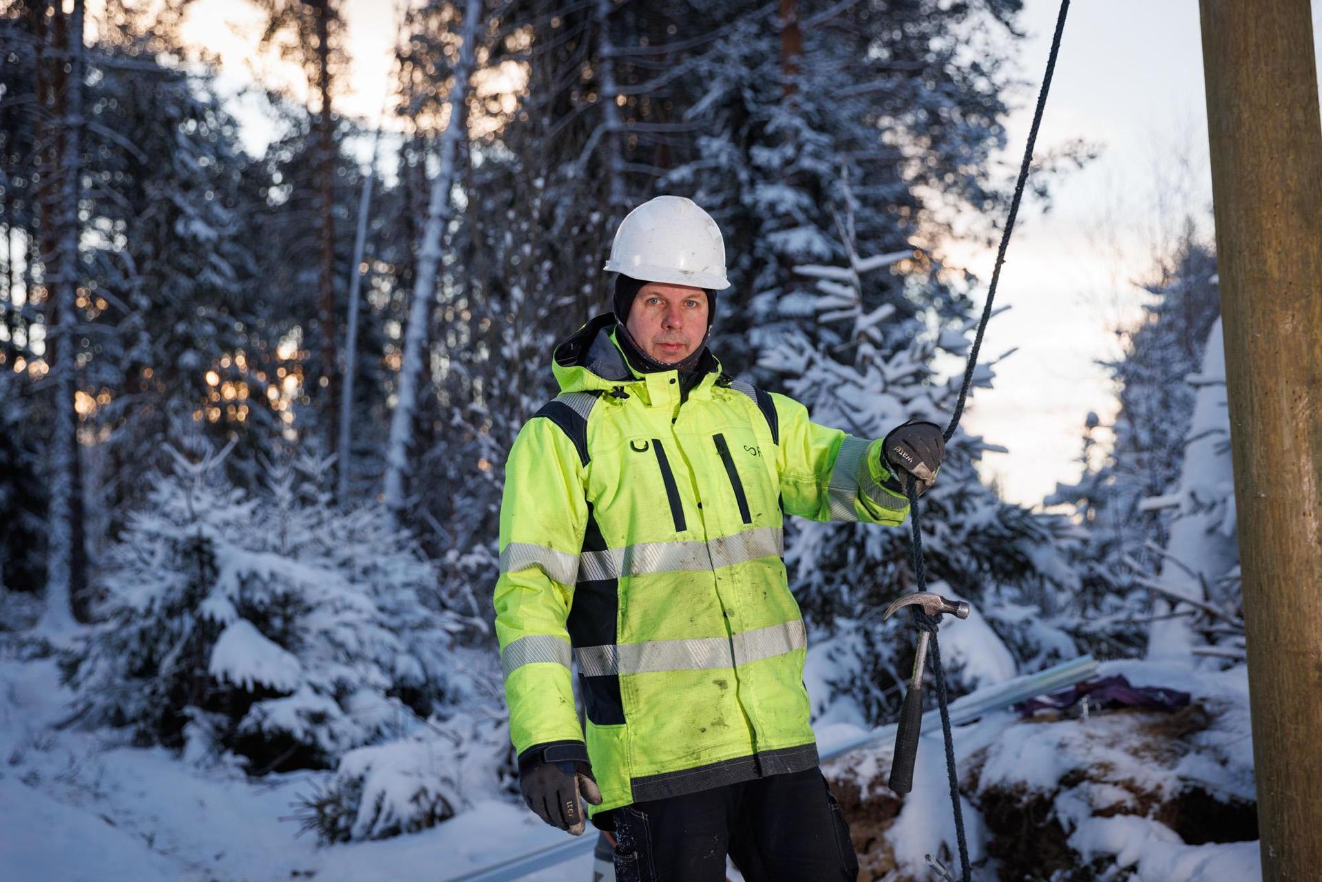 Mann som holder strømkabel fra mast